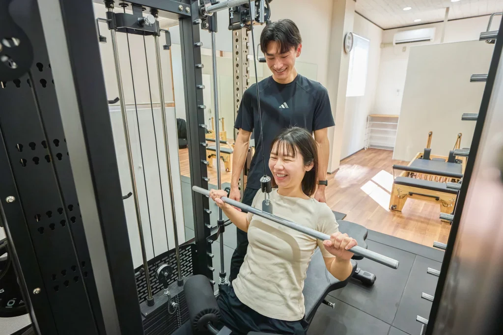 パーソナルトレーニングでバーベルを持ち上げる女性とトレーナー